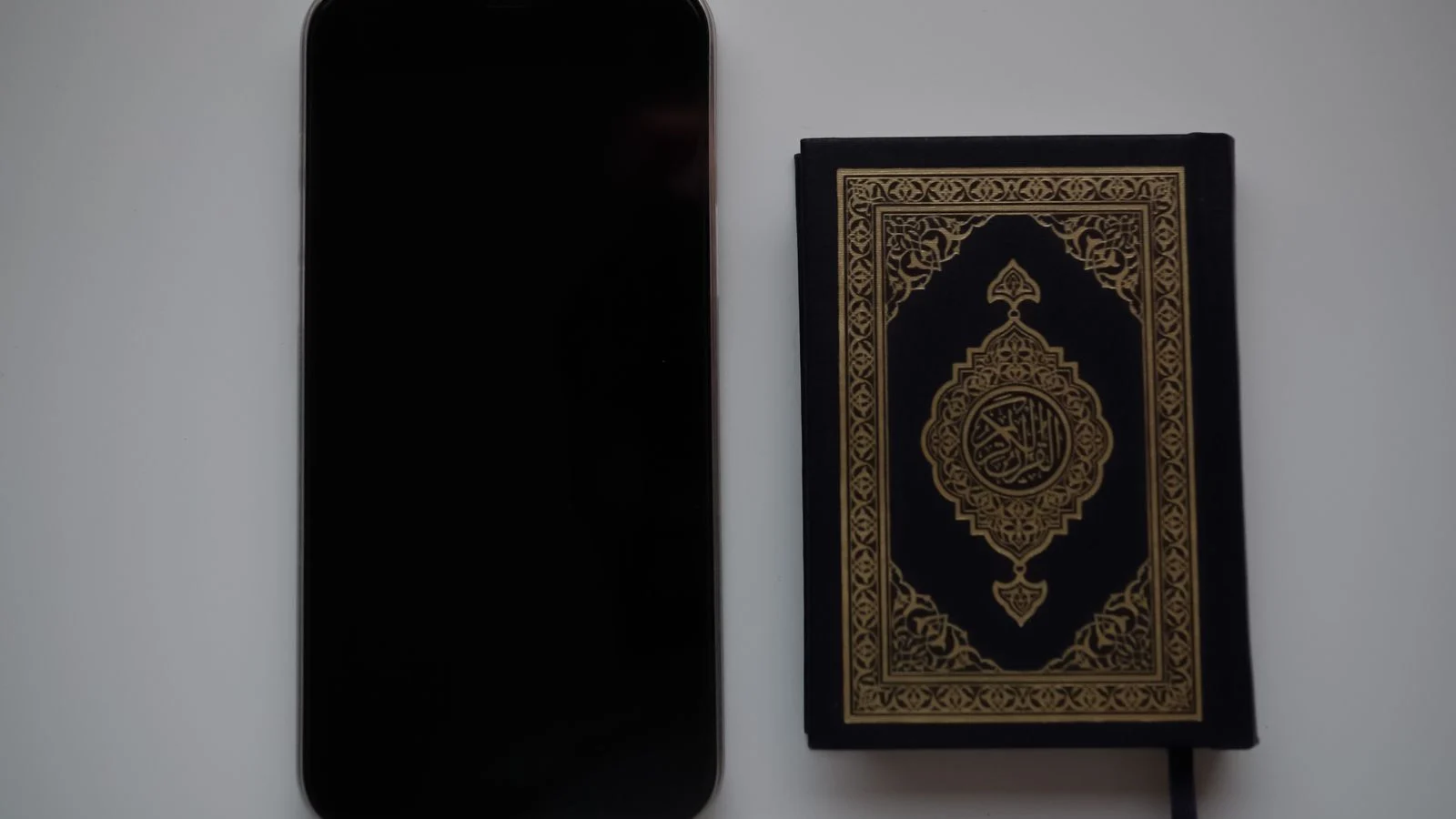 Quran and phone on a desk, ready for an evening online class