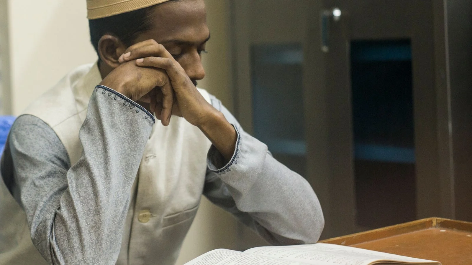 Adult student studying the Quran closely in a one-on-one lesson