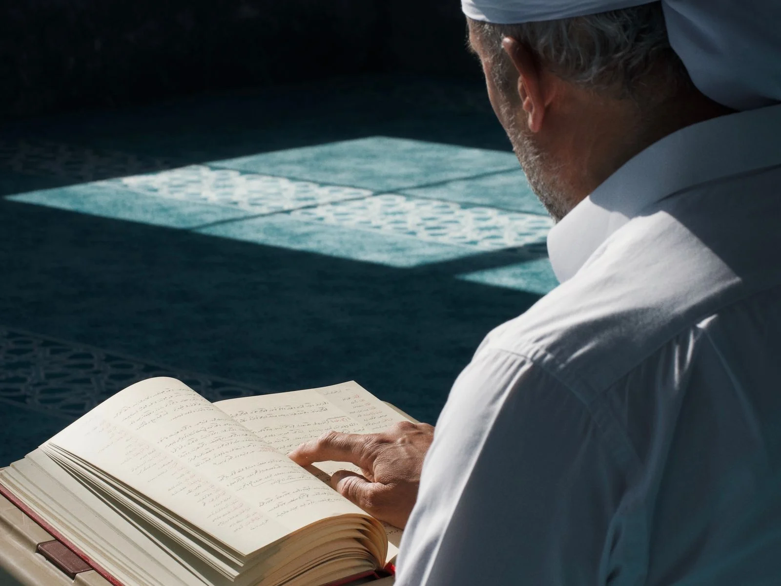 Adult man reading the Quran in a sunlit mosque