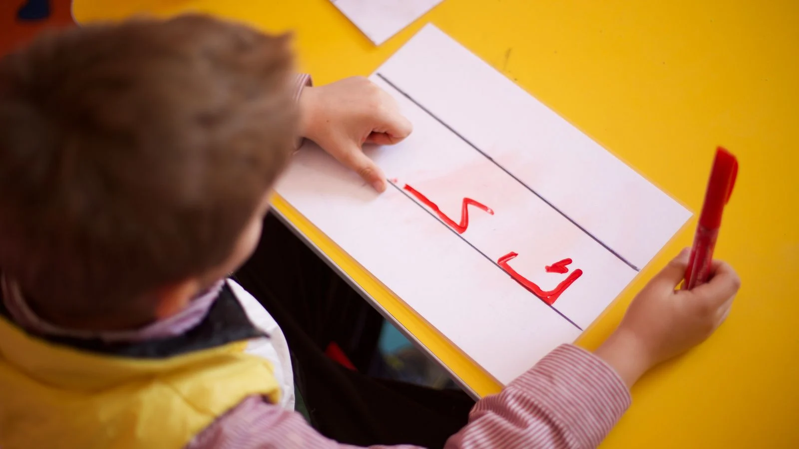 Child practicing the Arabic alphabet on paper