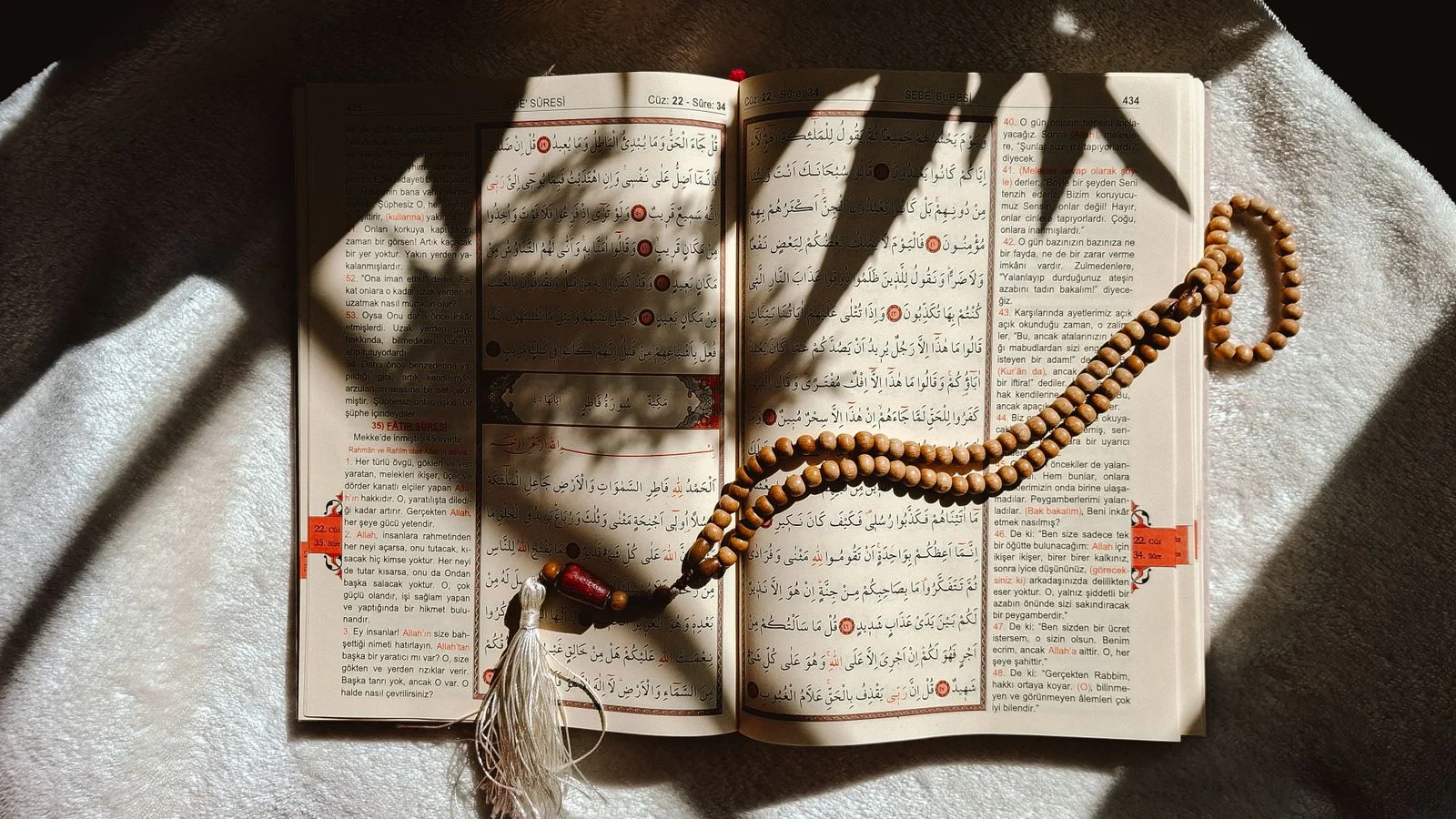 Open Quran with prayer beads in soft home light