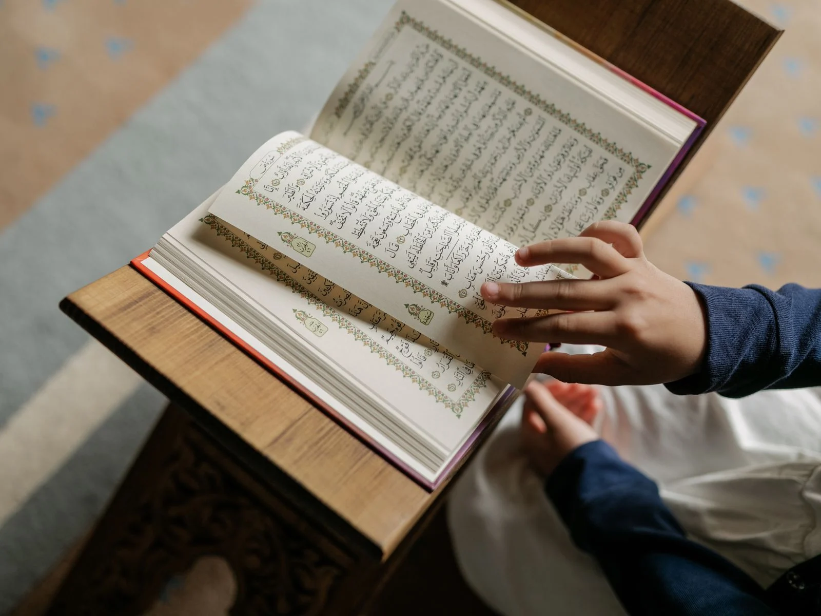 Young girl reading the Quran from a wooden stand