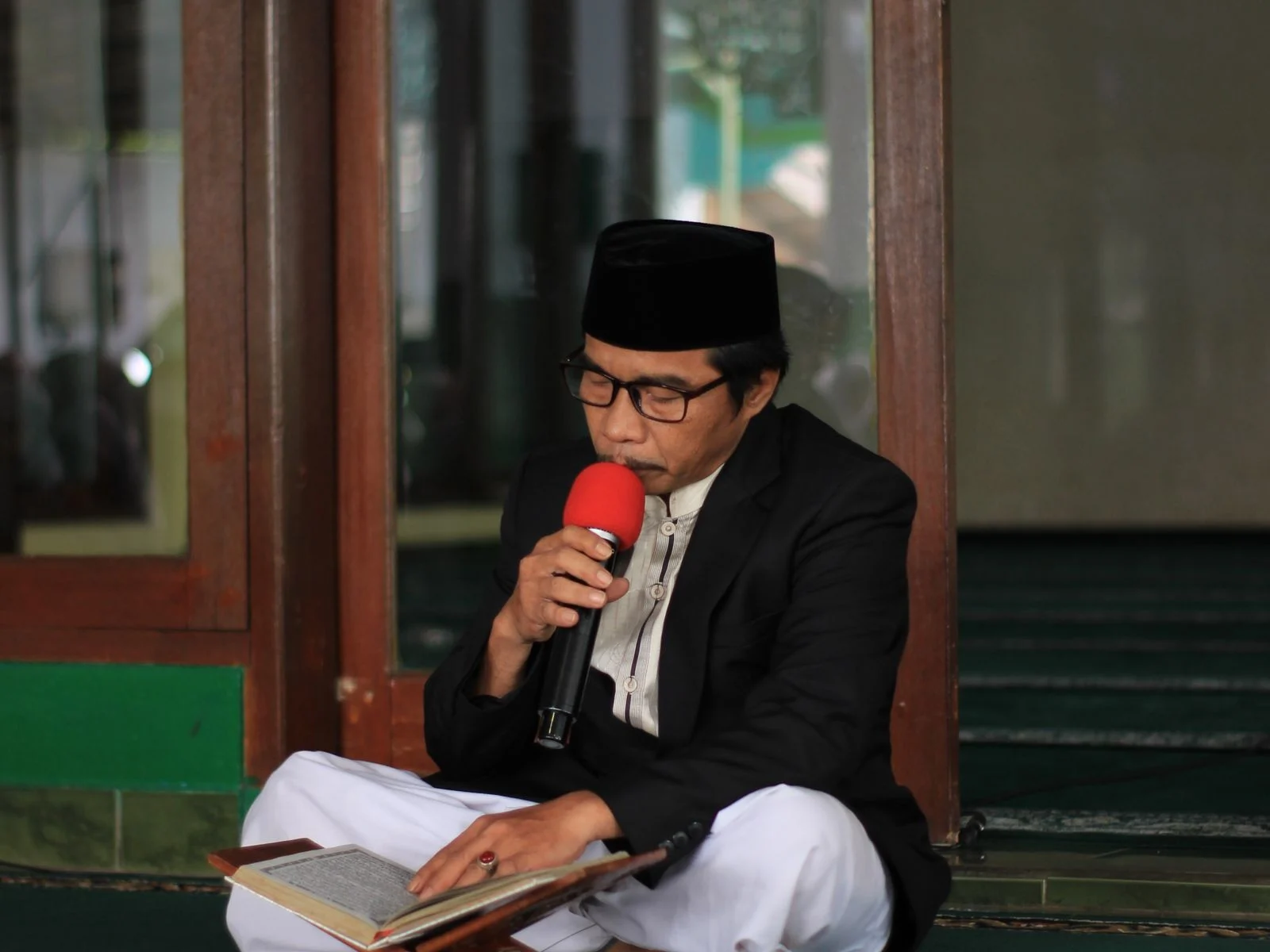 Man reciting the Quran into a microphone with correct Tajweed